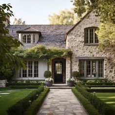 a stone house with trimmed hedges in front