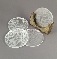 three white coasters sitting on top of a wooden box next to a piece of wood