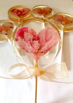 some pink flowers are in a glass vase on a white table with gold rimmed lollipops