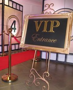 a sign that is sitting in front of a red carpet and some metal poles with signs on it