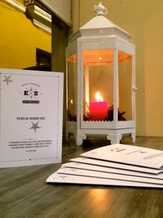 a lit candle sitting on top of a wooden table next to some papers and envelopes