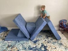 a young boy is playing on a blue slide in the corner of his living room