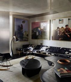 a living room filled with black furniture and pictures on the wall above it's coffee table