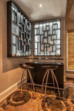 a bar with two stools in front of it and shelves on the wall behind it