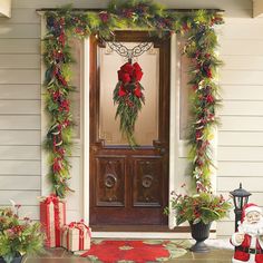 a front door decorated for christmas with wreaths and poinsettis on it