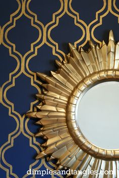 a mirror that is on the wall in front of a blue and gold wallpaper