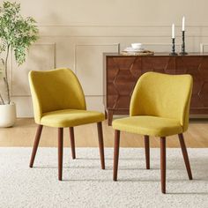 two yellow chairs sitting next to each other on a rug in front of a dresser