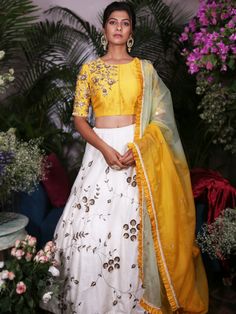 This stunning white lehenga with details of sequins, zardosi, pearls and glass pipes in jaal motifs on the bottom is teamed with a yellow blouse. The  outfit is completed with an ombre dupatta with scattered butis and ruffles at the hem. White Cutdana Set For Reception, White Silk Anarkali Set For Navratri, White Silk Set For Reception, White Silk Sets For Reception, White Raw Silk Dress With Cutdana, White Silk Set With Gota Work, Yellow Traditional Wear With Mirror Work In Tissue Silk, White Silk Sharara For Reception, White Silk Sets With Sheer Dupatta