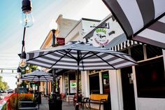 an outdoor cafe with tables and umbrellas on the sidewalk