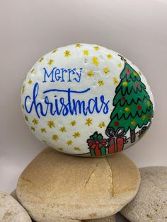 a merry christmas painted rock sitting on top of some rocks