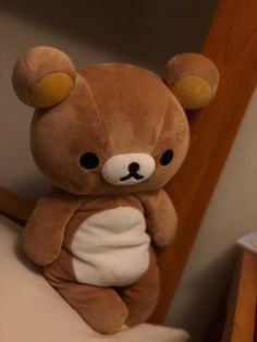 a brown teddy bear sitting on top of a bed