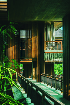 the inside of a building with lots of green plants in front of it and stairs leading up to the second floor