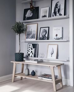 a wooden table sitting in front of a wall filled with pictures and framed photos on it