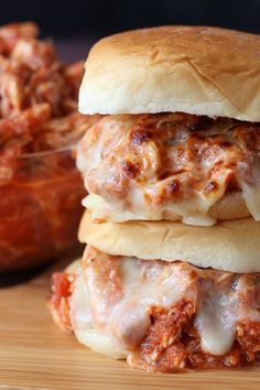 two sandwiches stacked on top of each other next to a bowl of spaghetti and sauce