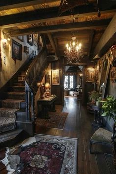 an old fashioned house with wood floors and chandeliers on the ceiling, stairs leading up to the second floor