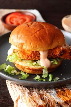 a chicken sandwich with lettuce and sauce on a black plate