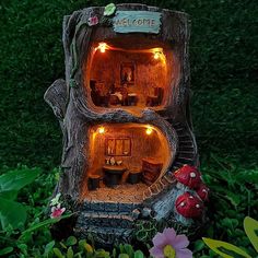 a doll house made out of a tree stump with lights on the outside and inside