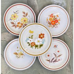 four plates with flowers painted on them are sitting on the ground next to each other