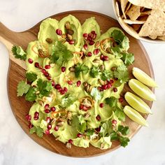 a wooden plate topped with guacamole and sliced apples