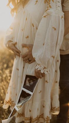 a pregnant woman holding her husband's belly in the middle of a wheat field