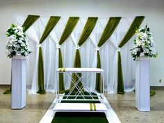 an aisle decorated with white flowers and green drapes