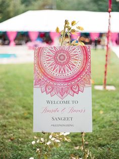 a welcome sign in front of a tent at an outdoor wedding ceremony with pink and white colors