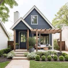 a small blue house with a porch and pergolated area in the front yard