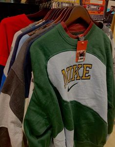 several sweatshirts are hanging on racks in a store, some with the word nike printed on them