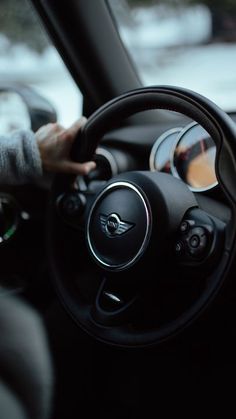 a person driving a car with their hand on the steering wheel