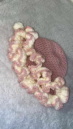 a crocheted hat laying on the floor next to a pile of yarns