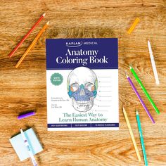 an anatomy coloring book with colored pencils and crayons on a wooden table