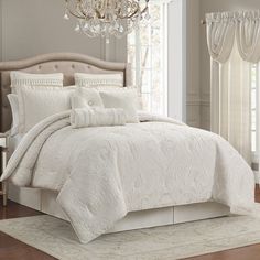 a white bed with a chandelier hanging from it's headboard in a bedroom