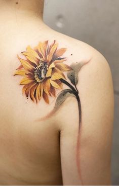 a sunflower tattoo on the back of a woman's upper arm and shoulder