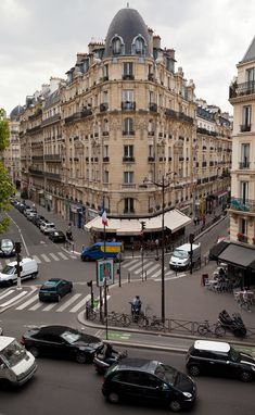 a busy city street filled with lots of traffic next to tall buildings and parked cars