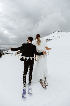 a bride and groom are walking in the snow