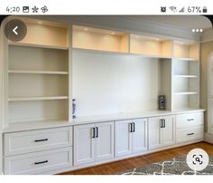 an empty living room with white cabinets and drawers on the wall next to a rug