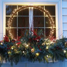 a window sill decorated with christmas lights and greenery in front of a white house