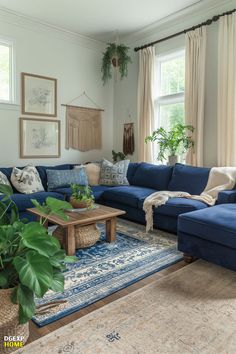 The bedroom features deep navy blue sofas complemented by a blue patterned rug. The walls are white, creating a stark but harmonious contrast. The space is accessorized with rustic wooden furniture and minimalistic boho decorations, crafting a serene and inviting atmosphere. Navy Blue And Yellow Living Room Ideas, Navy Blue Sofa And Cream Living Room, Decor With Blue Couch, Blue Couch Inspiration Living Rooms, Living Room Blue Couch Decor, Living Room Ideas With Blue Couch, Room With Navy Couch, Blue Black Wood Living Room, Rustic Blue Home Decor