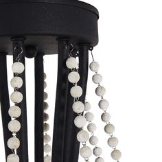 a black chandelier with white beads hanging from it's metal rods and chains