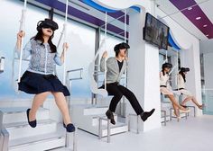 four people are sitting on swings in a room with blue and white walls, while one person is wearing headphones