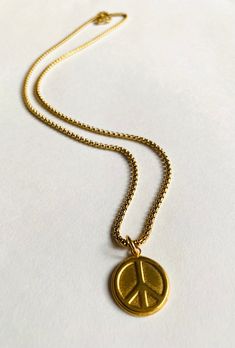 Long Peace Necklace Plated brass. Sturdy coin size charm of brass. Peace sign design. Sturdy long 22" gold over steel chain. Steel lobster clasp. Super fun to wear and layer with other necklaces. Long Peace Necklace Adjustable Gold Medallion Charm Necklaces, Gold Adjustable Round Disc Charm Necklaces, Gold Medallion Charm Necklace, Brass Medallion Charm Necklace With Vintage Charm, Brass Round Pendant Charm Necklace With Vintage Charm, Gold-tone Medallion Charm Necklace With Adjustable Chain, Brass Round Pendant Charm Necklace, Gold Coin Necklace With Adjustable Chain For Everyday, Everyday Gold Medallion Necklace