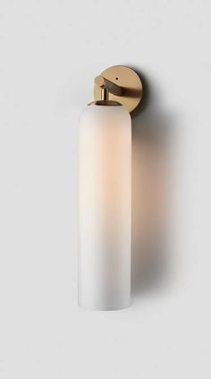 a light that is on the wall with a white glass shade and gold metal fittings