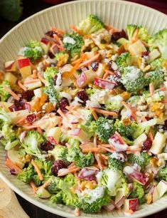 a salad with broccoli, apples, cranberries and other toppings