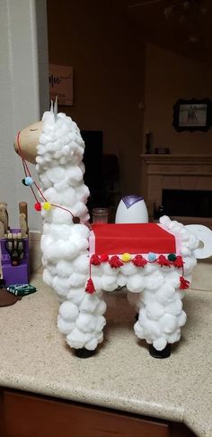 a llama made out of cotton sitting on top of a counter next to an egg