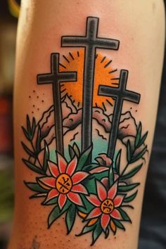 a tattoo with three crosses and flowers on it