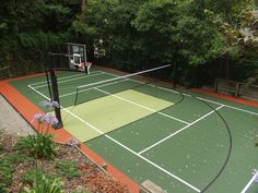 an outdoor basketball court surrounded by trees and flowers in the middle of a garden area