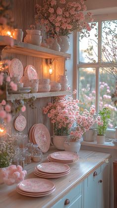 pink flowers are in vases and plates on the counter top next to a window