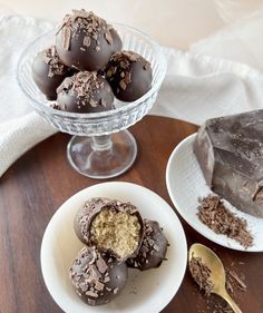 chocolate truffles are sitting on plates next to a glass bowl full of dark chocolate