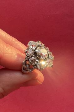 a woman's hand is holding an old diamond ring with diamonds on the side