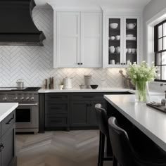 a kitchen with black and white cabinets, counter tops, and an island in the middle